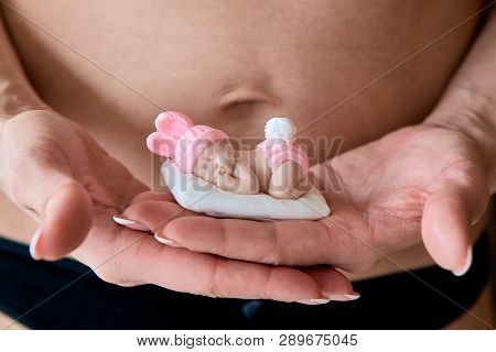 Pregnant Young Woomen Holds A Figurine Of Soap In The Shape Of A Newborn Baby Girl In Front Of Her B