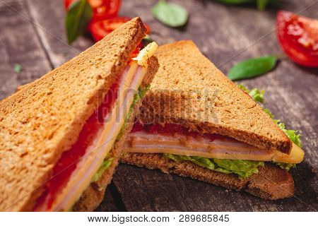 Sandwich With Ham, Cheese, Tomatoes And Lettuce Leaves On Wooden Rustic Table. Close Up
