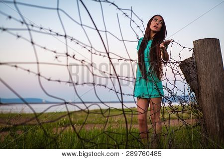 Portrait Of Young Beautiful Girl In A Turquoise Dress Near Barbed Wire In Summer Outdoor