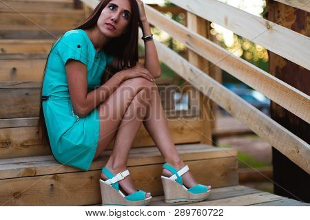 Girl In Turquoise Short Dress Sitting On A Tree Log