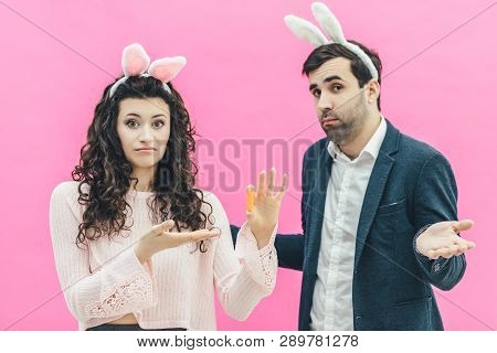 Young Happy Couple On The Pink Background. On The Head Is A Rabbit Ears. A Young Girl Holding Small 