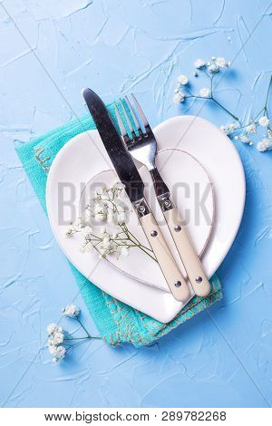Plates In Form Of Hearts, Napkin, Knife And Fork And  Fresh White Gypsofila  Flowers On Blue Texture