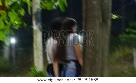 Blurred Image Two Young Women Are Standing In Conversation.