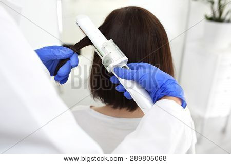Keratin hair straightening and nutrition. A woman during a keratin treatment using a hair straighten