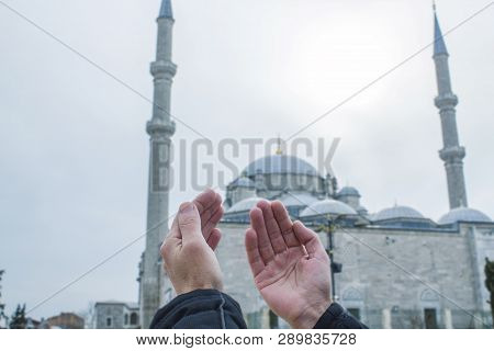 Muslim Man Raising Hand And Praying With Mosque Background