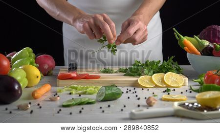 Man Is Cutting Parsley Leaves In The Kitchen