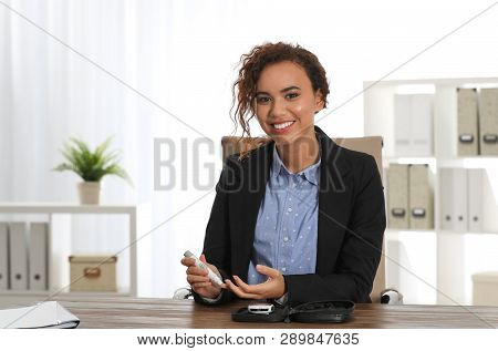 Young African-american Woman Using Lancet Pen At Workplace. Diabetes Control