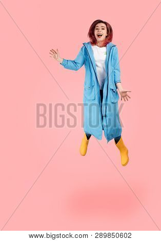 Full Length Size Shot Of Carefree Beaming Woman Jumps In Air Against Pink Background, Being Sportive