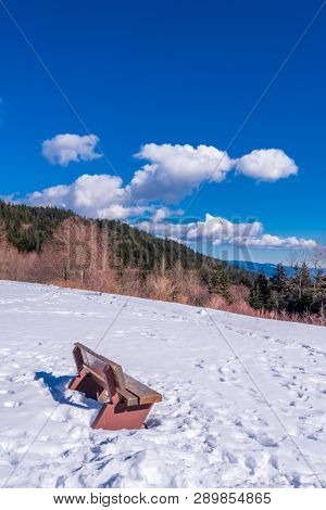 A park bench with gorgeous view at mountains and blule sky with white clouds, British Columbia, Canada.