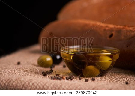 Fresh Bread Baguette With Olive Oil, Olives. Cheese And Rosemary On Wooden Background. Teasty Breakf