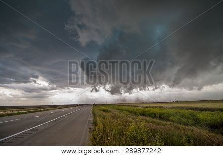 Severe Winds From A Dark Storm Cloud Blow Dirt Across A Highway On The Plains.