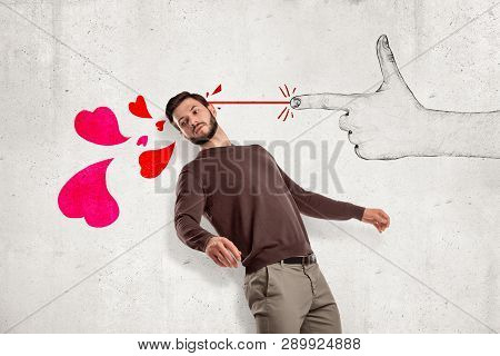 Young Handsome Man In Casual Clothes Standing In Half-turn Near Wall And Leaning Back As If From Han