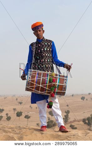 BIKANER, INDIA - JANUARY 12, 2019: Young Indian drummer in traditional clothes performing during Cam