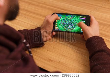 Prague, Czech Republic - March 16, 2019: Man Holding A Smartphone And Playng The Clash Of Clans Mobi