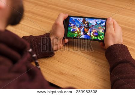 Prague, Czech Republic - March 16, 2019: Man Holding A Smartphone And Playng The Clash Of Clans Mobi