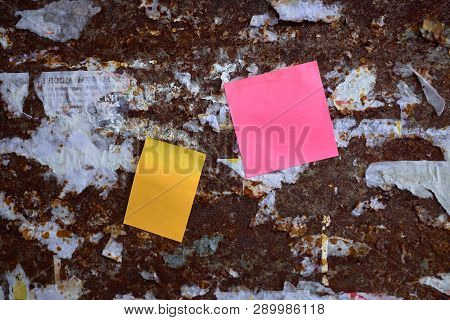 Two Blank Color Paper On Torn Posters On Rusted Steel Wall. A Lot Of The Torn-off Announcements Are 