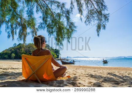 Woman enjoying her holidays on a transat at the tropical beach in Thailand