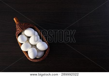 Easter Eggs In The Duck Basket. Wicker Basket Of Straw. Festive Meal On A Dark Wooden Table. Feast O