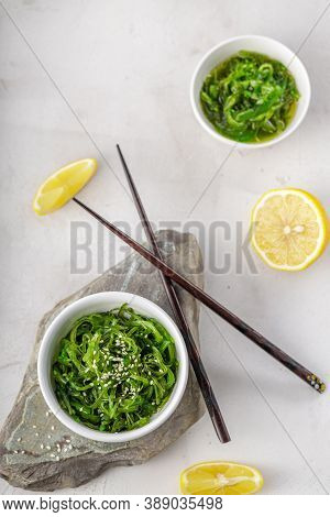 Croped Photo Of Green Wakame Seaweed Salad With Chopstick And Lemon At The Restaurant