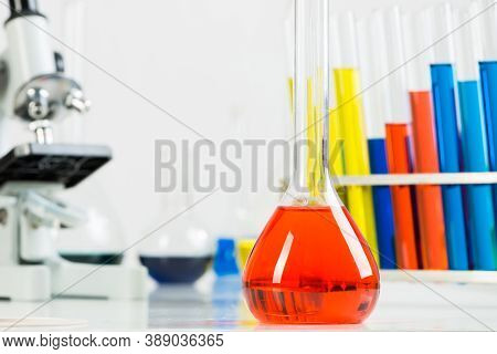 Chemistry Lesson In School Lab. Glass Test Tubes With Color Reagents And Microscope Standing On Desk