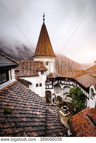 Bran, Romania - 30 November 2019: Bran Castle roofs on misty mountains background