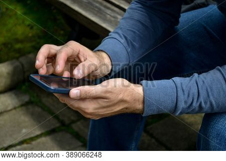 Man Using The Phone. Mobile In Hand. Person In Dark Clouthes With Smartfone.