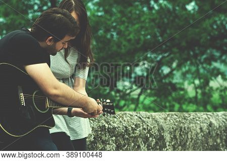Older Brother Teaching His Younger Sister To Play Guitar In The Nature. Beautiful Moments Spent Toge