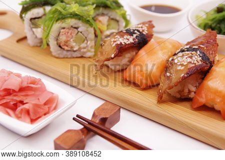 Japanese Sushi Food On A Wooden Tray, Served With Ginger, Soy Sauce And Seaweed Salad. Salmon Nigiri