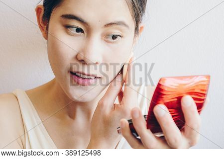 Portrait Of Asian Woman Applying Foundation Powder Puff On Her Face To Cover Flaws And Change The Na