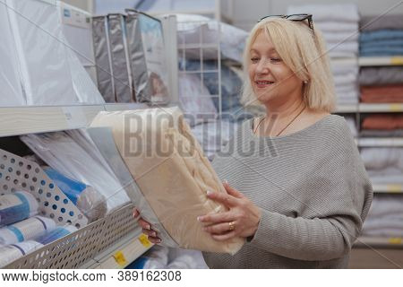 Mature Cheerful Woman Smiling, Choosing New Bedsheets At Furnishings Store. Happy Female Customer Bu