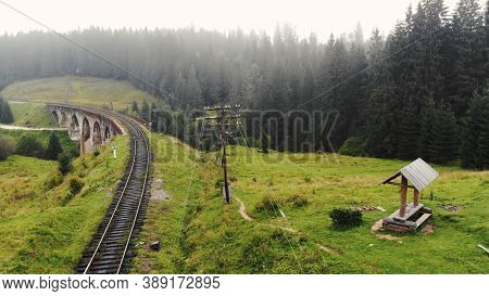 Scenery Of The Railroad Bridge. Rural Sump On The Green Hill. Pole With Electrical Wires.
