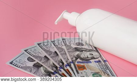A White Antiseptic Pump Bottle And Money On A Light Pink Background