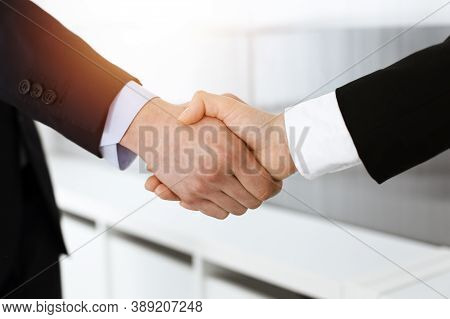 Businessman And Woman Shaking Hands In Sunny Office, Close-up. Concept Of Handshake As Success Symbo