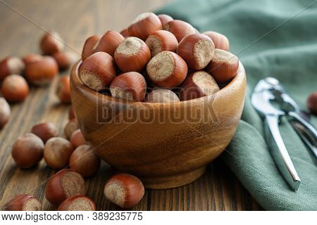 Wooden Bowl Of Hazelnuts And Nutcracker On Table.