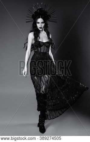 Halloween Theme: Attractive Young Witch In Black Dress And Headgear With Roses And Spikes. Dark Beau