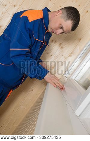 A Man In Clothes For Repair Seals Window Cracks With A White Selicon