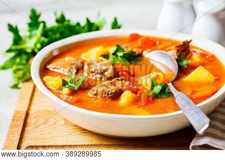 Soup With Beef And Vegetables In A White Plate On A Wooden Board. Traditional Meat Shurpa Soup With 