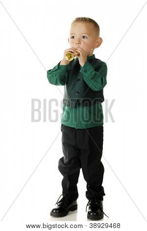 Un'adorabile, vestito da bambino in età prescolare che soffia il suo piccolo tromba d'oro.   Su uno sfondo bianco.