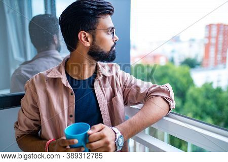 Arabian Man In Casual Dress Holning A Blue Cup And Looking Dreamly