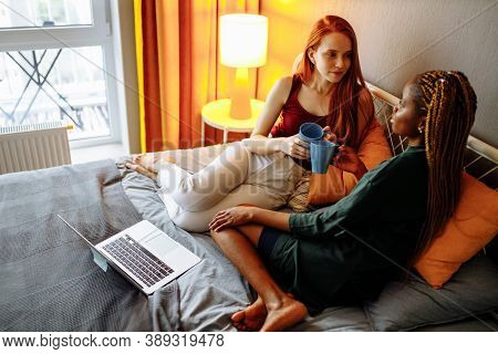 Cheerful Afro And European Lesbian Women At Home On The Bed
