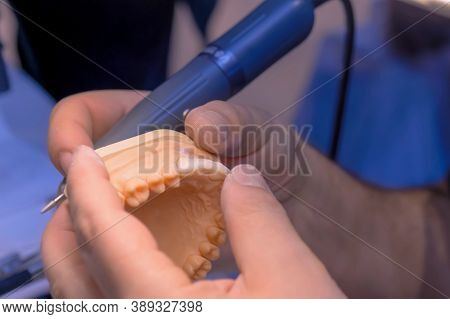Professional Dental Technician Or Dentist Holding Motor Handpiece Tool And Working With Dental Prost