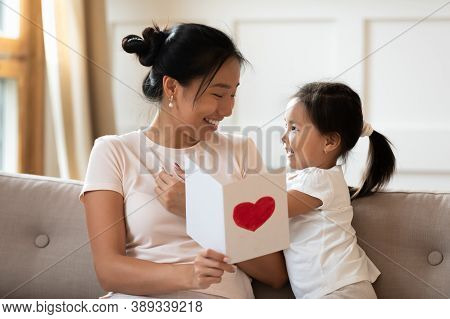 Smiling Asian Mother Holding Greeting Card, Little Girl Congratulating Mum