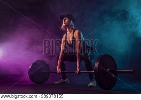 Side View Of Female Bodybuilder Doing Deadlift Using Barbell. Srtong Woman With Muscular Body In Spo