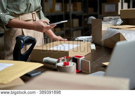 Female Small Business Owner Using Mobile App On Smartphone Checking Parcel Box. Warehouse Worker, Se