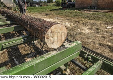 Mobile Sawing Equipment For Logs In The Open Air. Rural Landscape On A Sunny Day. Mobility And Work 