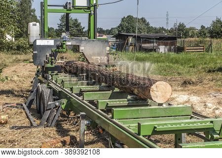 Mobile Sawing Equipment For Logs In The Open Air. Rural Landscape On A Sunny Day. Mobility And Work 