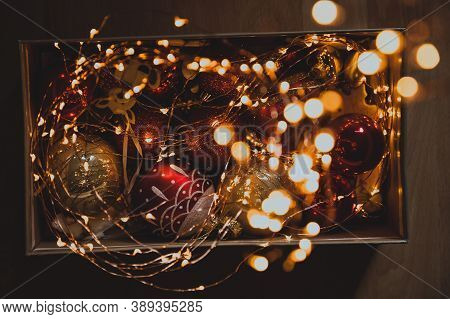 Christmas balls, dolls and lights in a box on a wooden table for Christmas celebrations