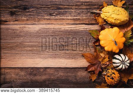 Autumn Leaves With Colorful Pumpkins Over A Textured Vintage Rustic Wooden Background With Copy Spac