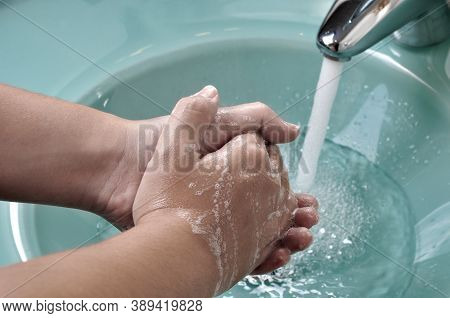 Hands Being Washed In A Green Sink During The Coronavirus Pandemic