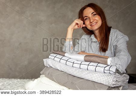 Beautiful Woman In Winter Thick Warm Robe Is Sitting And Neatly Folding Bed Linens And Bath Towels